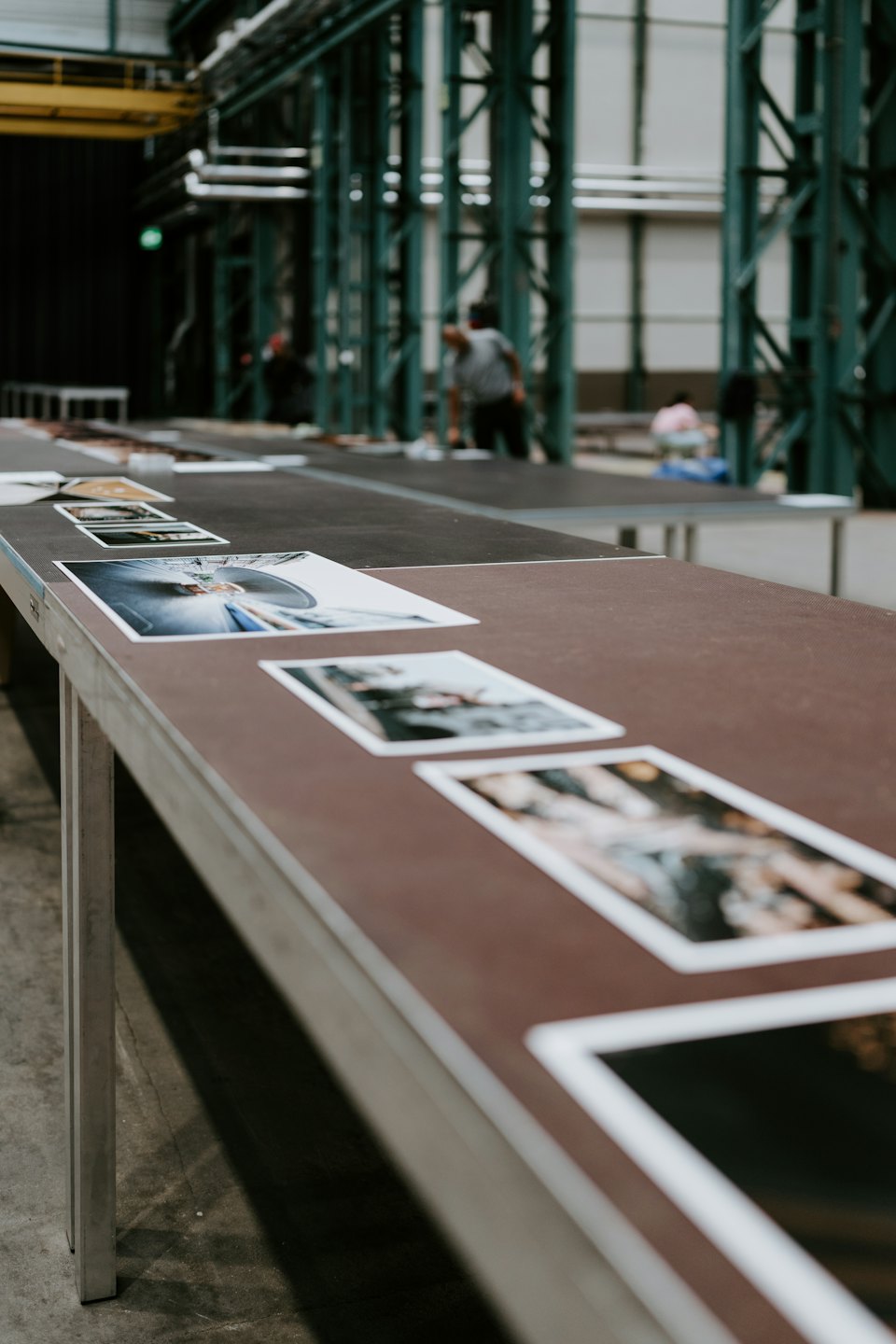 Impresiones fotográficas expuestas sobre mesas en un taller industrial.