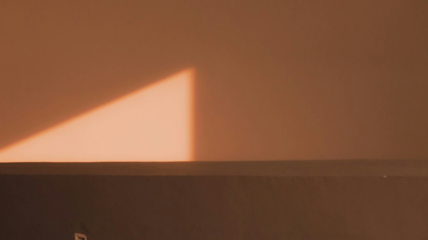 Un haz de luz triangular ilumina una pared texturizada.
